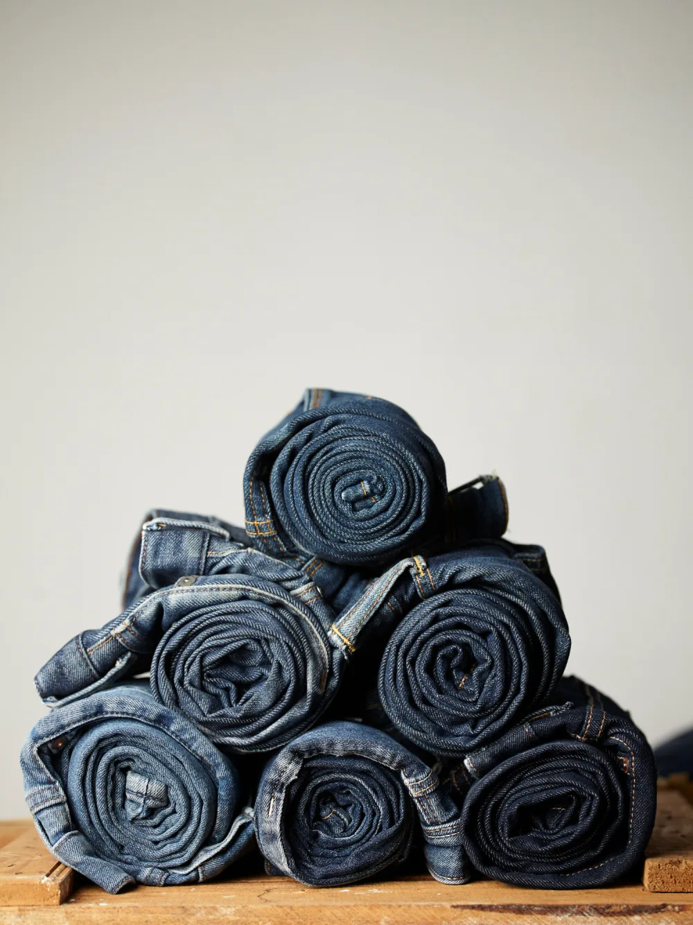 Rolled denim jeans stacked on a workbench